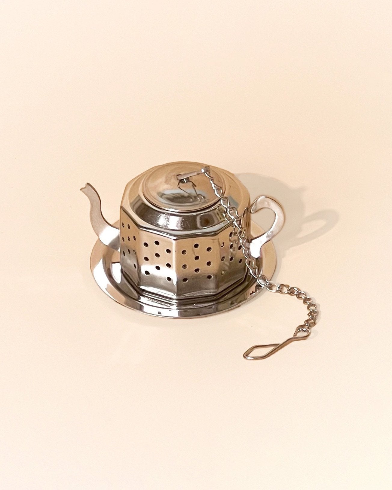 An teapot shaped infuser in silver color