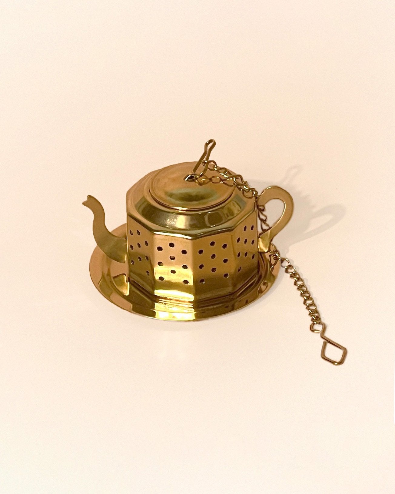 An teapot shaped infuser in gold color