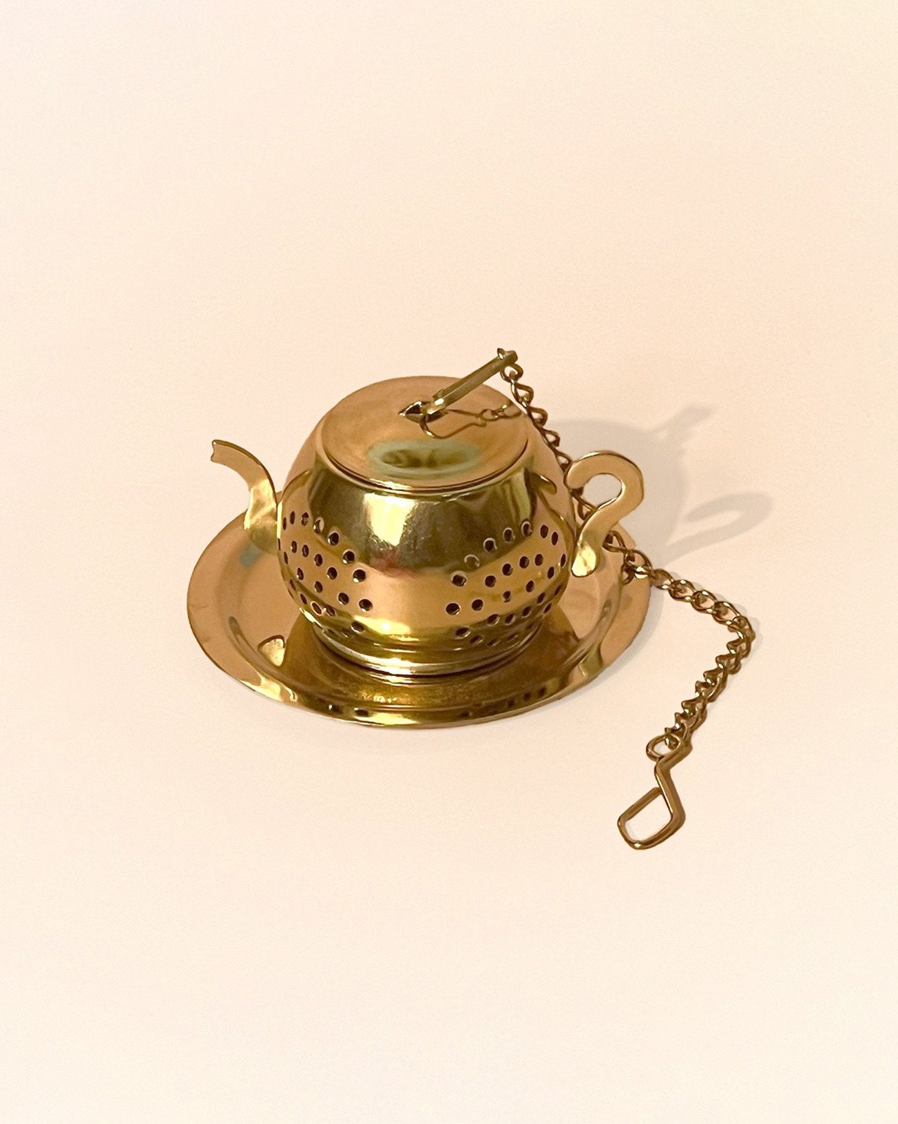 An little teapot shaped infuser in gold color