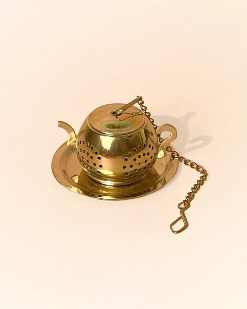 An little teapot shaped infuser in gold color